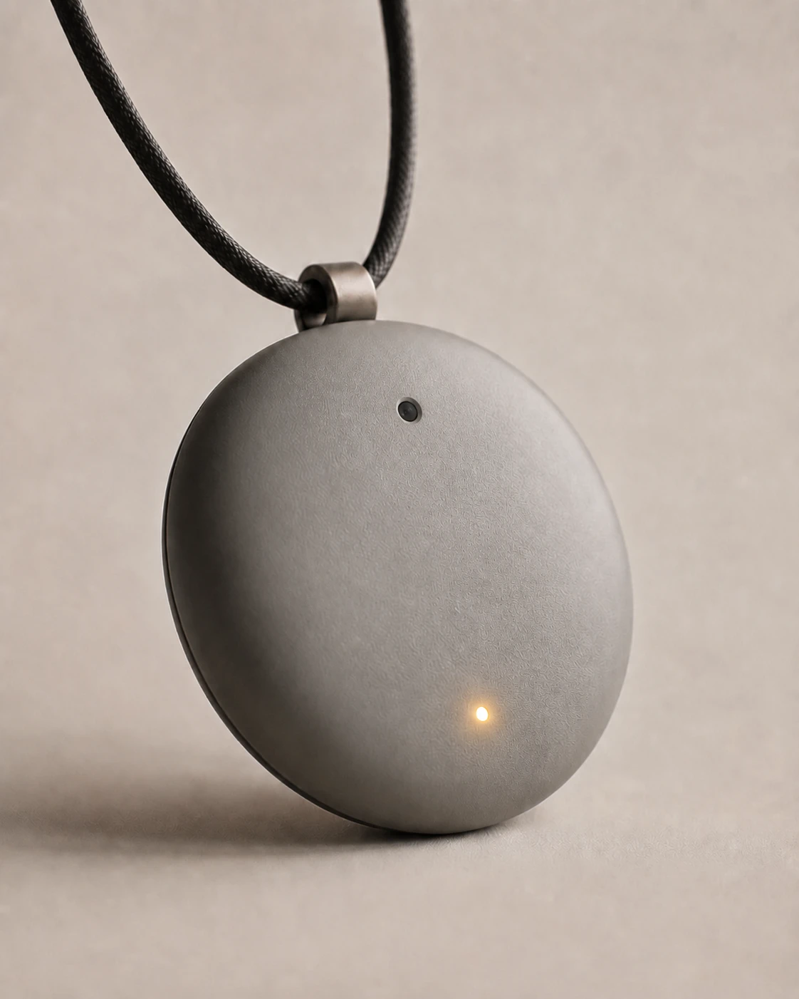 The Syntropic Labs Pendant, a circular pendant with an integrated memory camera worn on a cord.